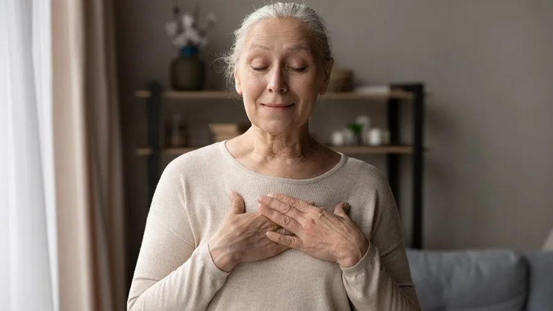A woman sits in her living room and practices mindfulness